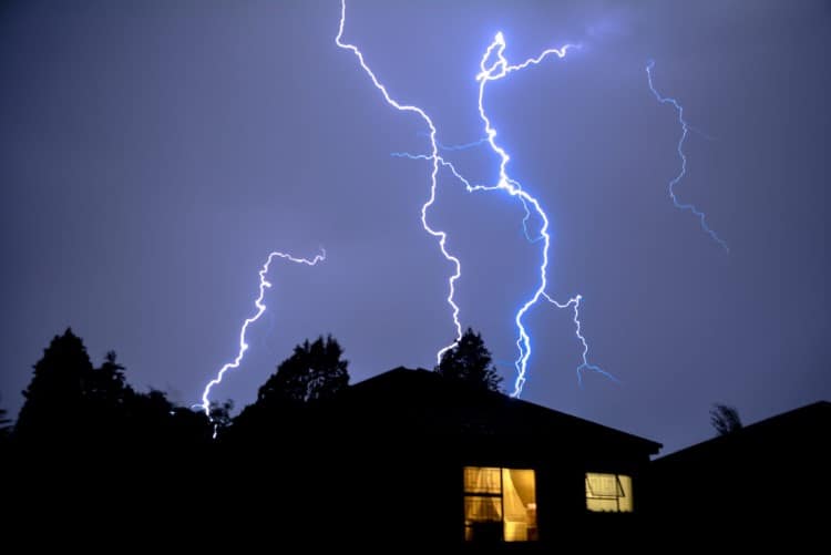 Cloud to Ground Electric Lightning behind house roof tops